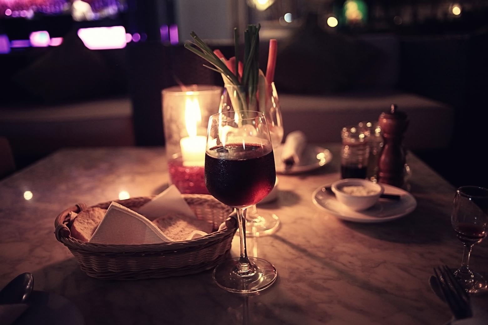 Glass of red wine on a candlelit restaurant table.