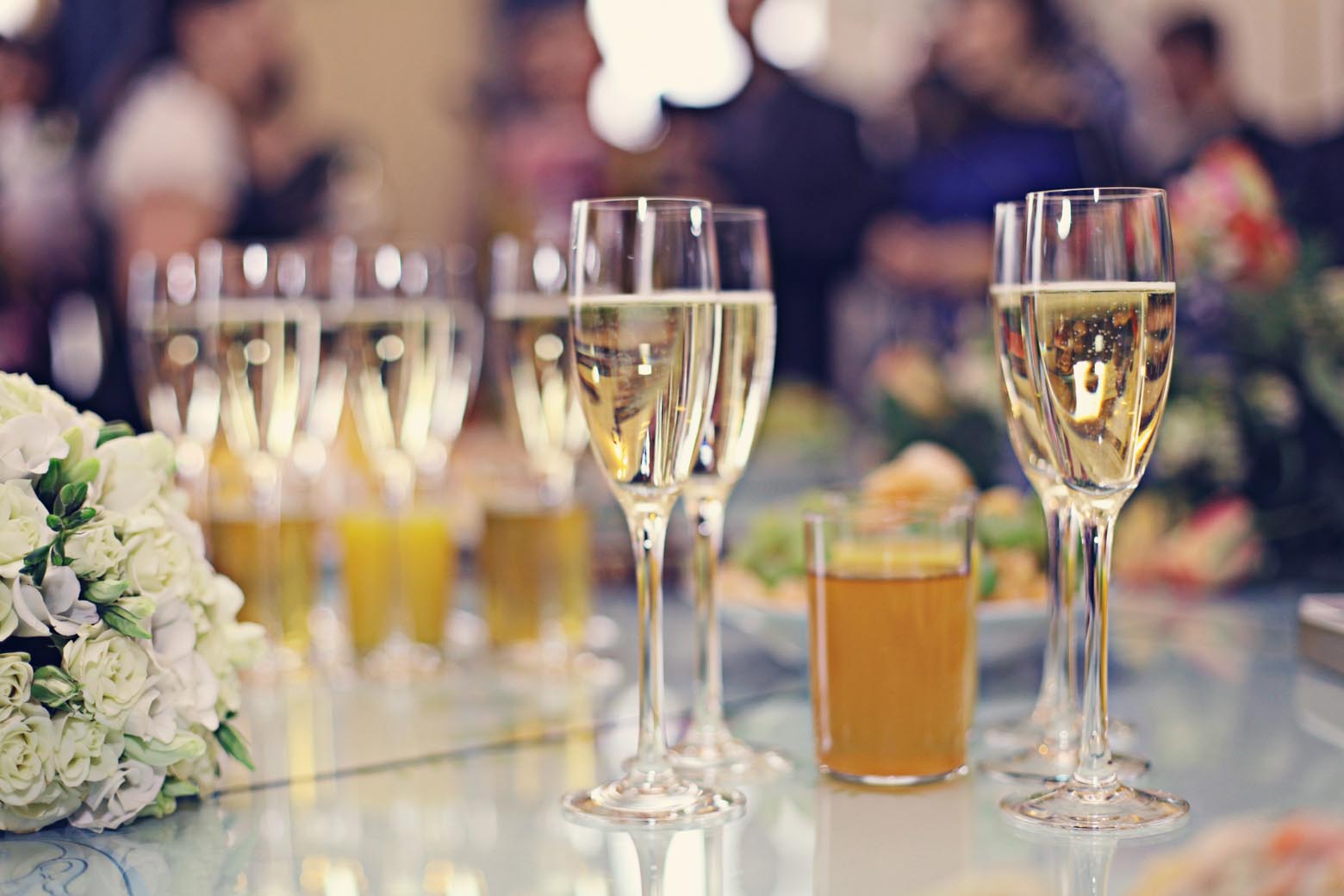 Champagne flutes arranged beside a white floral centerpiece.